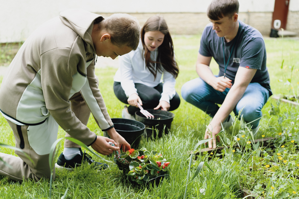 Young people and carer gardening at a home.